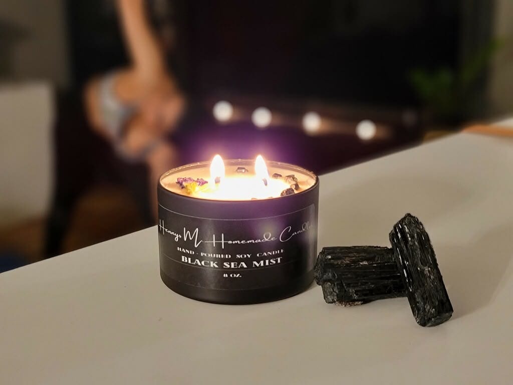 Black Sea Mist candle burning beside a piece of raw black tourmaline
